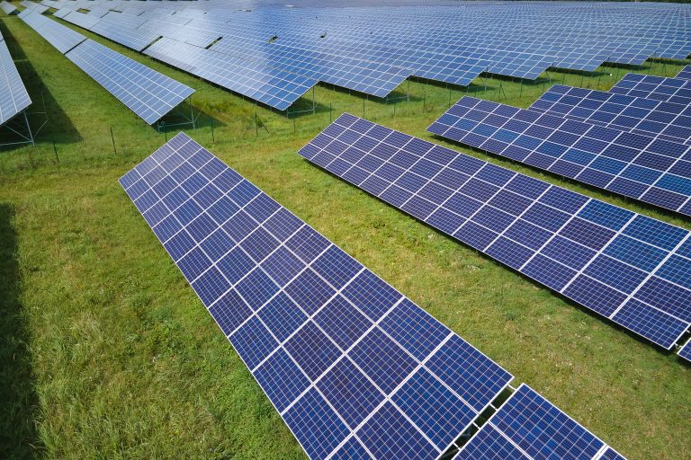Aerial view of large sustainable electrical power plant with rows of solar photovoltaic panels for producing clean electric energy. Concept of renewable electricity with zero emission.
